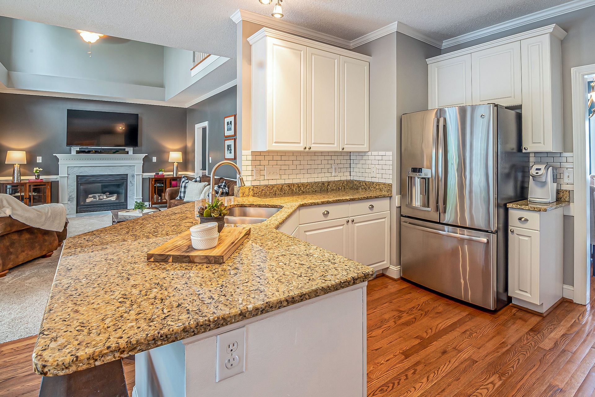 Luxurious open-concept kitchen with granite countertops and modern appliances, flowing into a cozy living room with a fireplace.